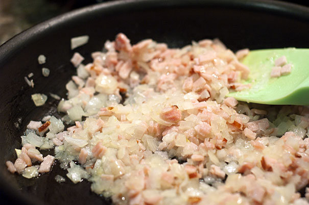 diced onions and bacon frying in a pan