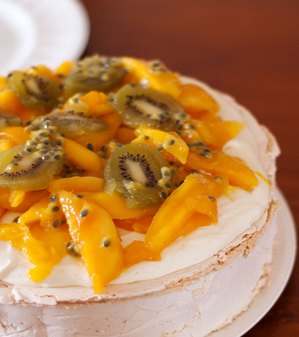 Pavlova topped with whipped cream and mango